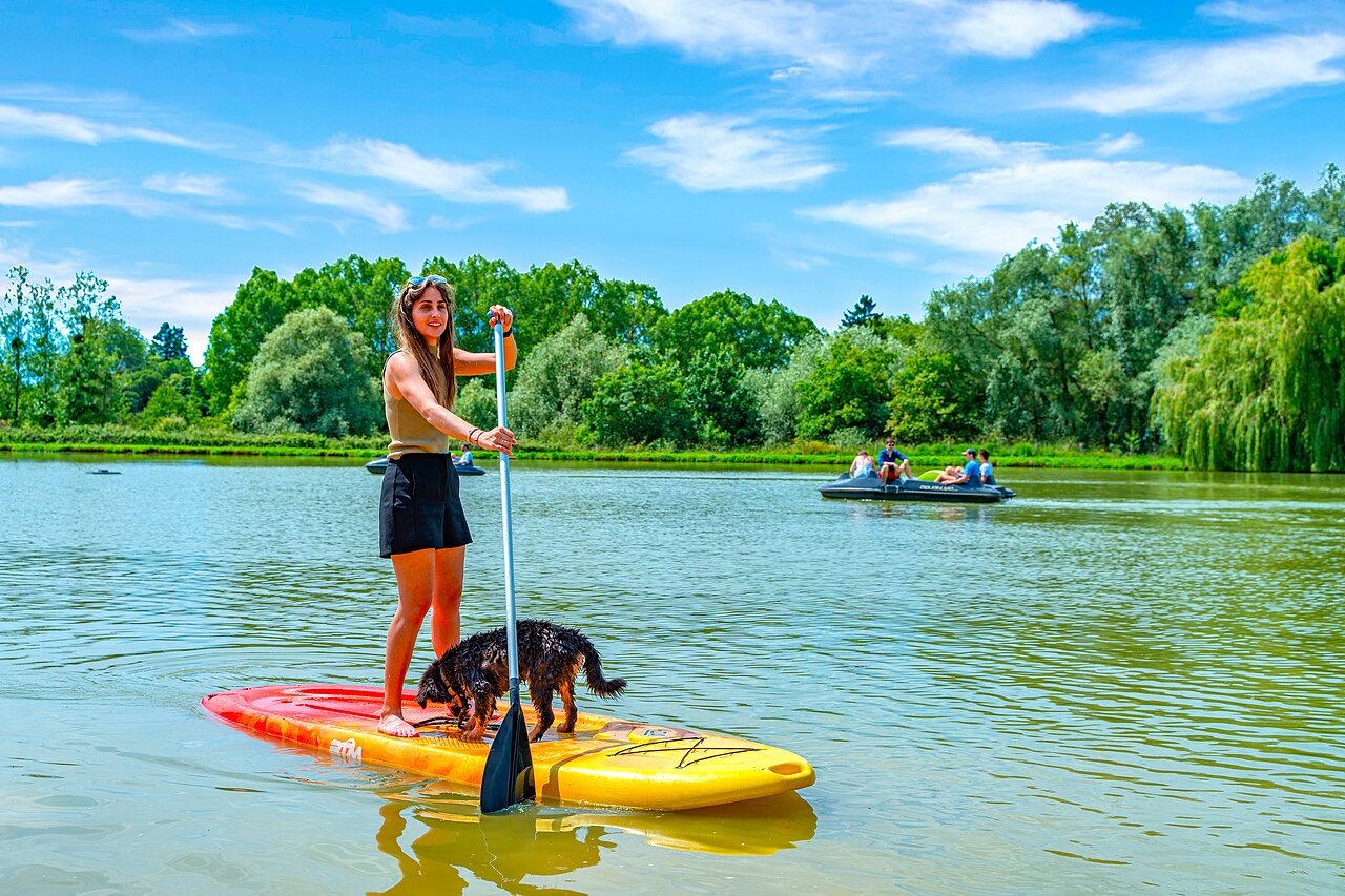Woman and dog on stand-up paddleboard on the lake at CAPFUN Grand Cerf campsite in Gimouille (58).