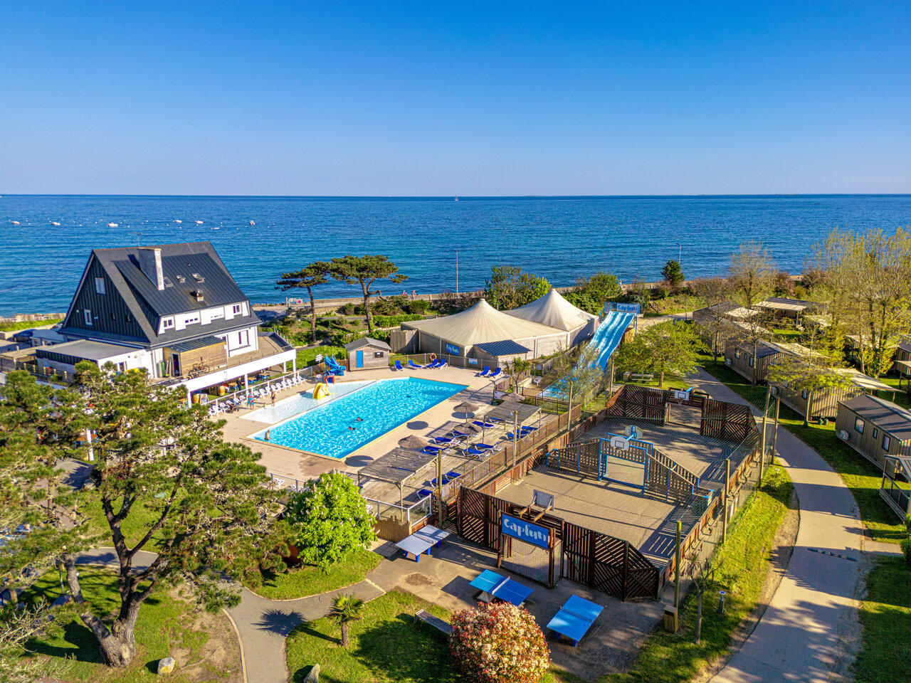 Outdoor pool, water slide and multi-sport court at CAPFUN Grand Large campsite in FOUESNANT (29).