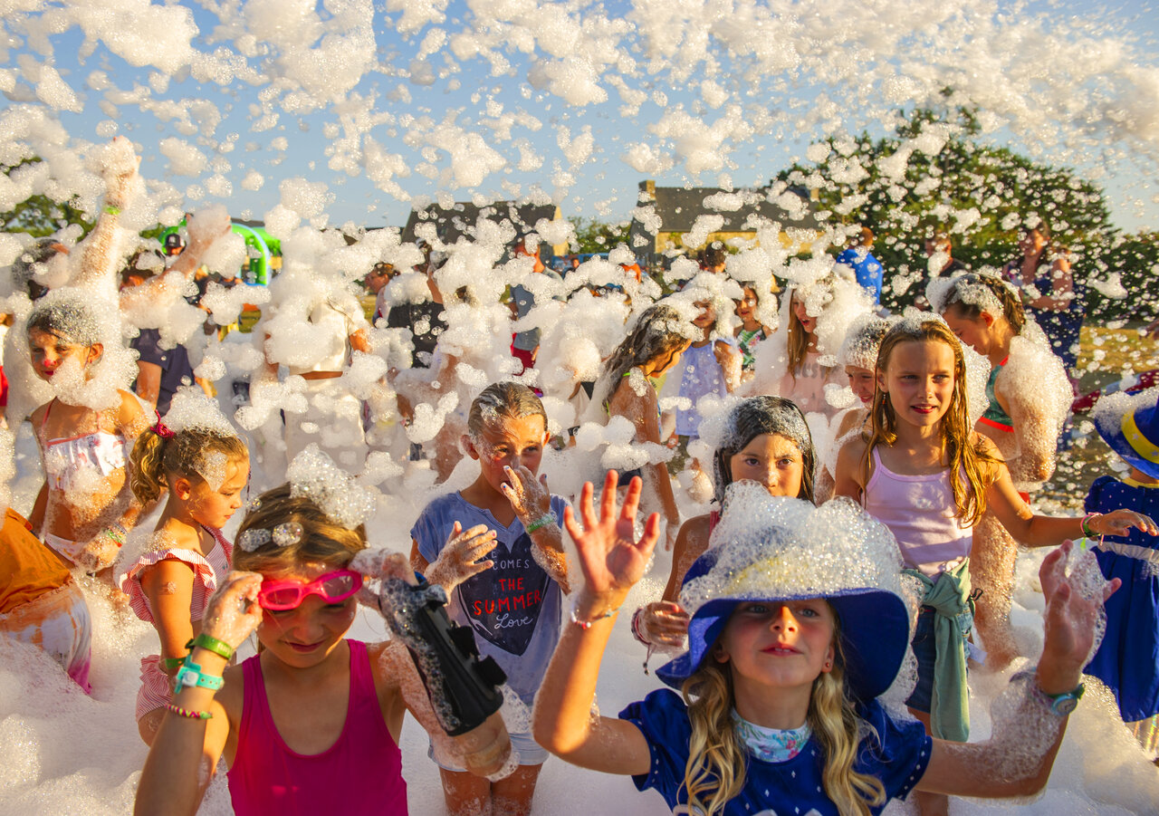 Happy children enjoying a lively foam party animation at CAPFUN Grand Large campsite in FOUESNANT (29).