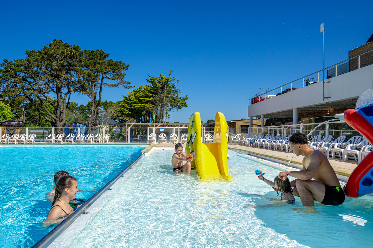 Outdoor swimming pool and slide at CAPFUN Grand Large campsite in FOUESNANT.