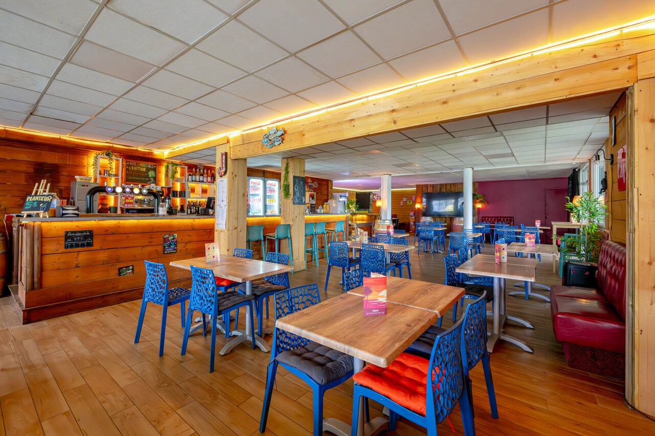 Bar and restaurant area with tables and chairs at CAPFUN Grand Large campsite in FOUESNANT (29).