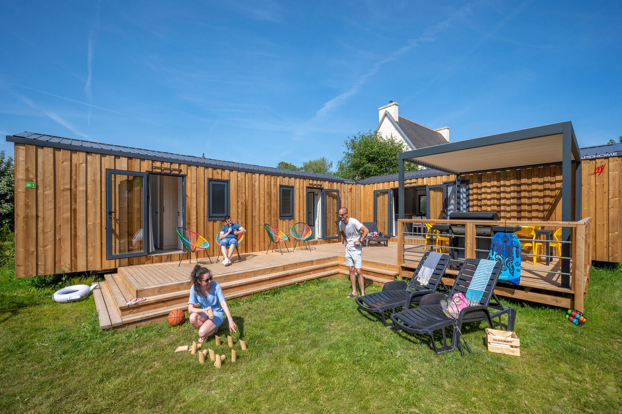 Modern mobile homes with wooden deck and outdoor games at CAPFUN Grand Large campsite in FOUESNANT (29).
