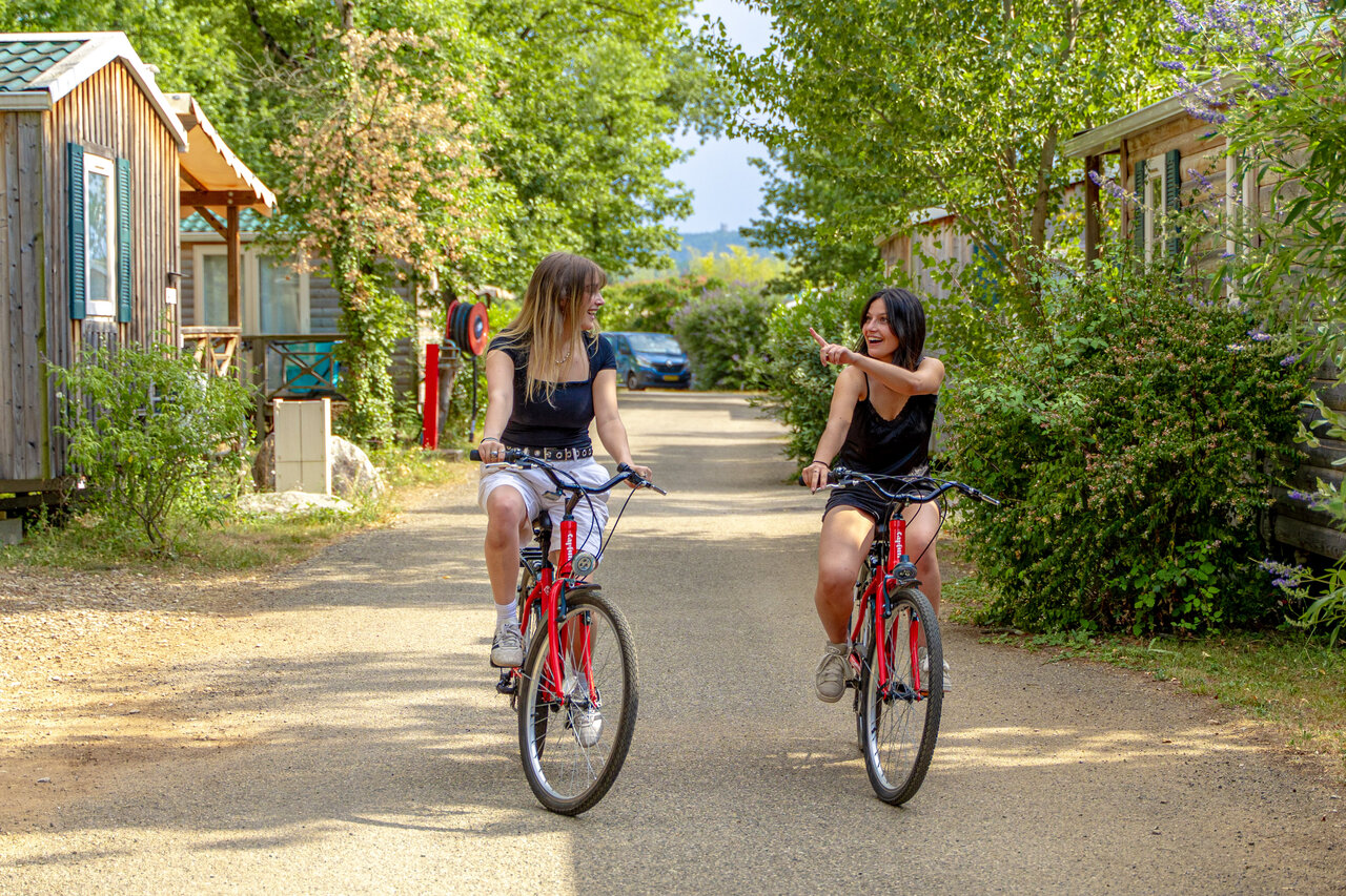 Friends cycling on path, mobile homes, at CAPFUN Grand Lierne campsite in CHATEAUDOUBLE.