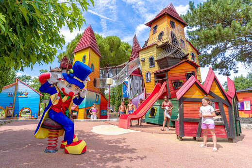 Colorful playground with slide and mascot at CAPFUN Grand Lierne campsite in CHATEAUDOUBLE (26).