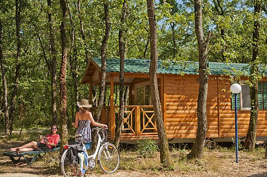 Mobile home, vacationers and bicycle at CAPFUN Grand Lierne campsite in CHATEAUDOUBLE (26).