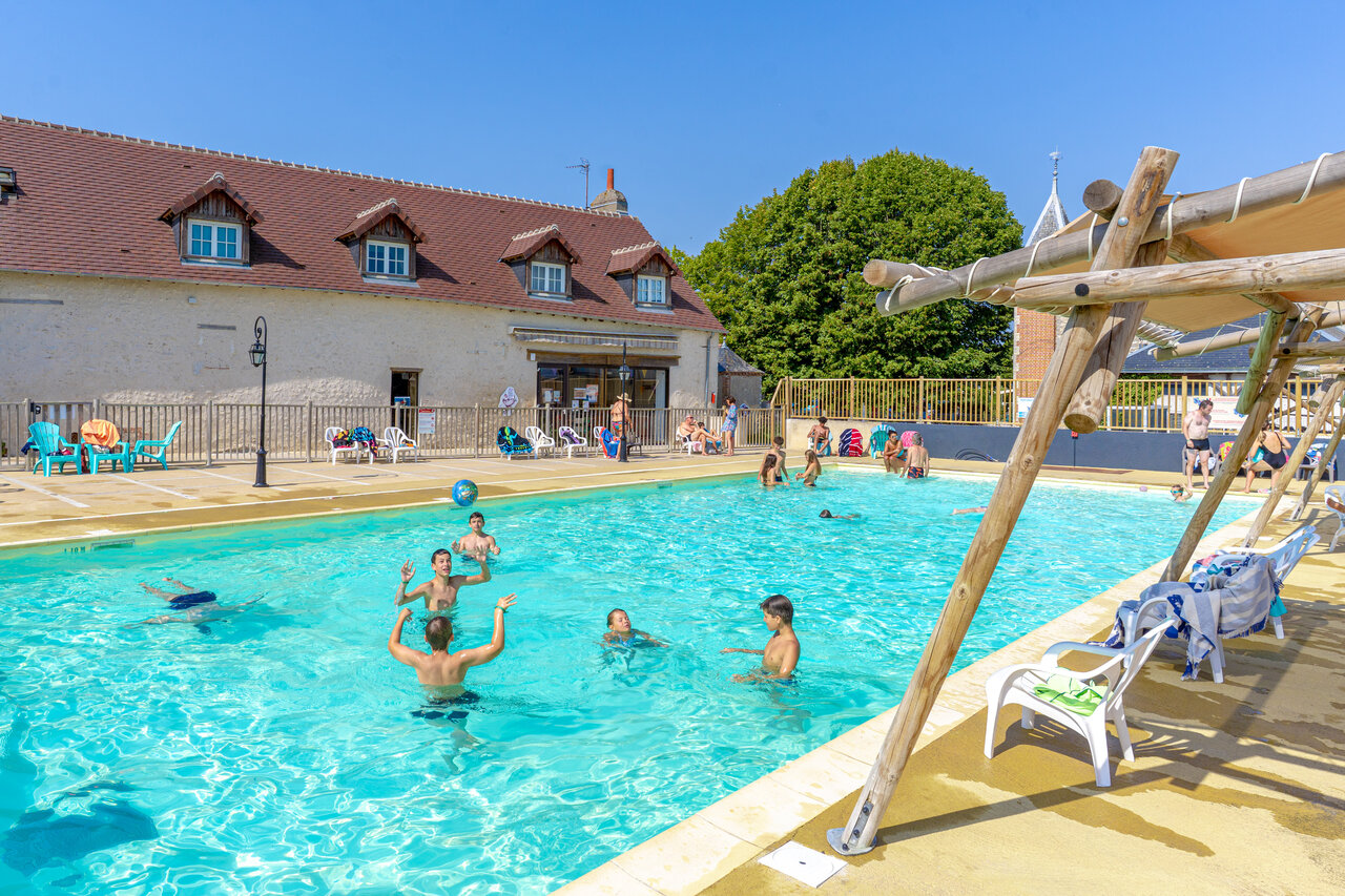 Lively outdoor swimming pool with children playing ball at CAPFUN Grenouill�re campsite in Su�vres (41).