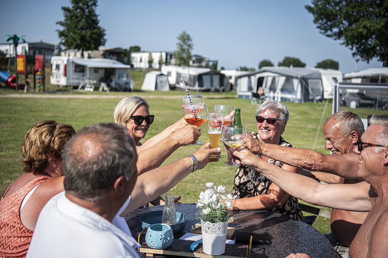 Senior friends joyfully toasting on a campsite pitch at CAPFUN Groene Eiland.