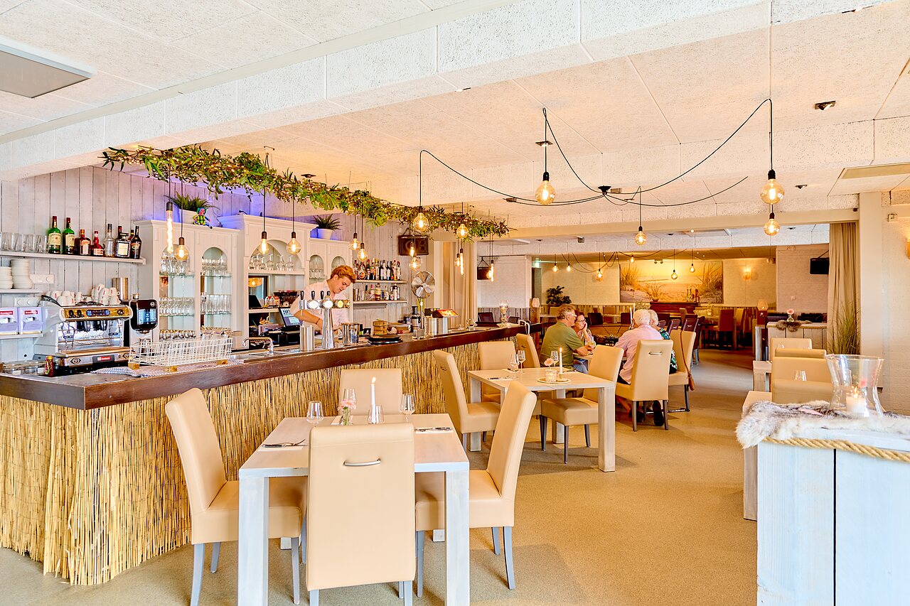 Modern restaurant and bar with tables at CAPFUN Groene Eiland campsite in Appeltern.