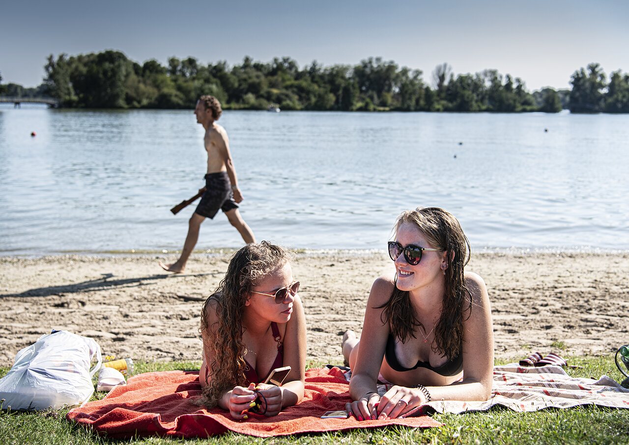 Two young women relaxing on beach at CAPFUN Groene Eiland campsite Appeltern.