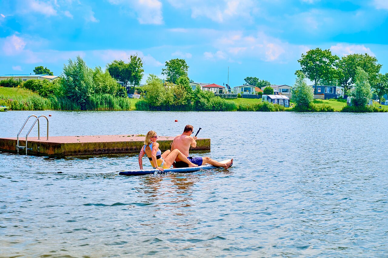 Couple paddleboarding on the lake at CAPFUN Groene Eiland campsite in Appeltern.