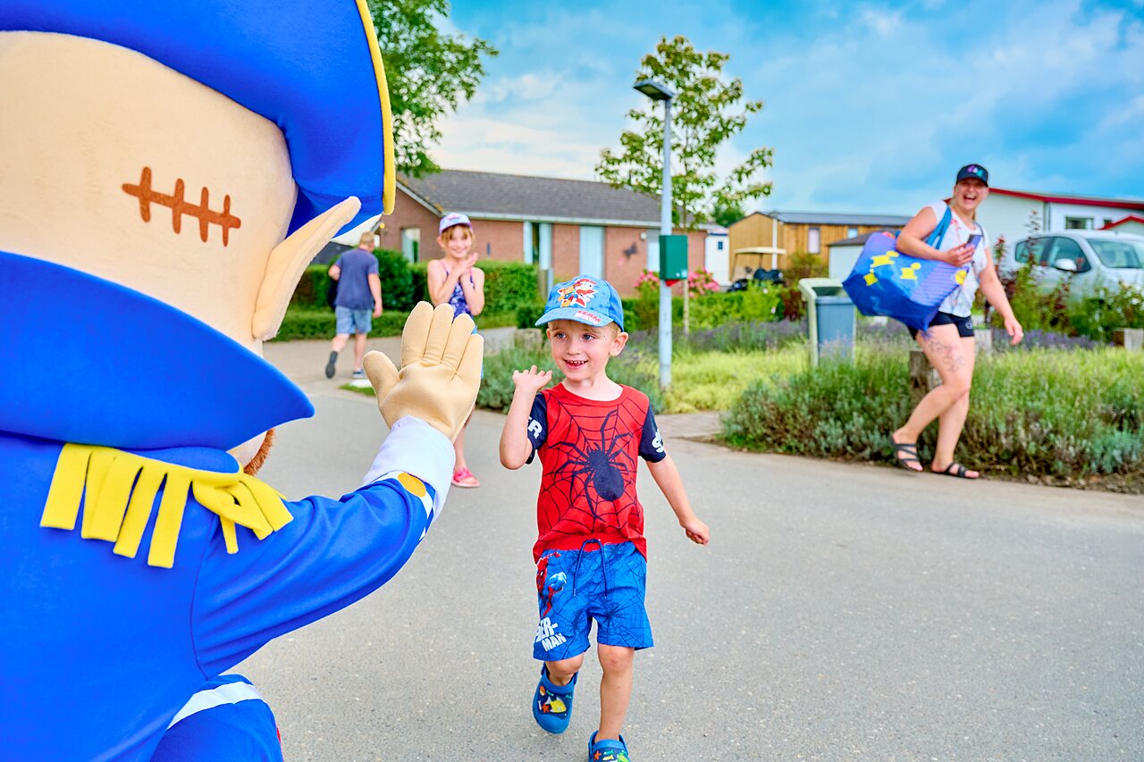 Mascot waving to a smiling child during animation at CAPFUN Groene Eiland campsite in Appeltern.
