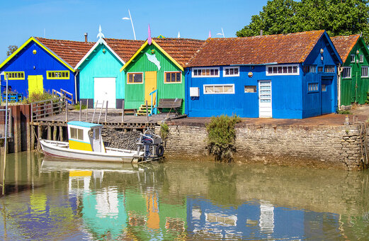 Colorful oyster huts and fishing boat in a typical Charente-Maritime village.