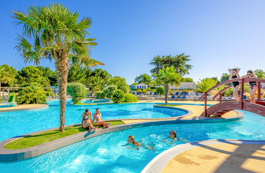Outdoor swimming pool, river and bridge at VAGUES OCEANES Grosses Pierres campsite.