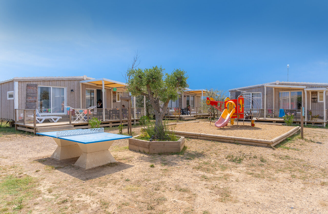 Mobile homes with terraces, playground, and ping-pong table at VAGUES OCEANES Hamacs campsite in Fleury (11).