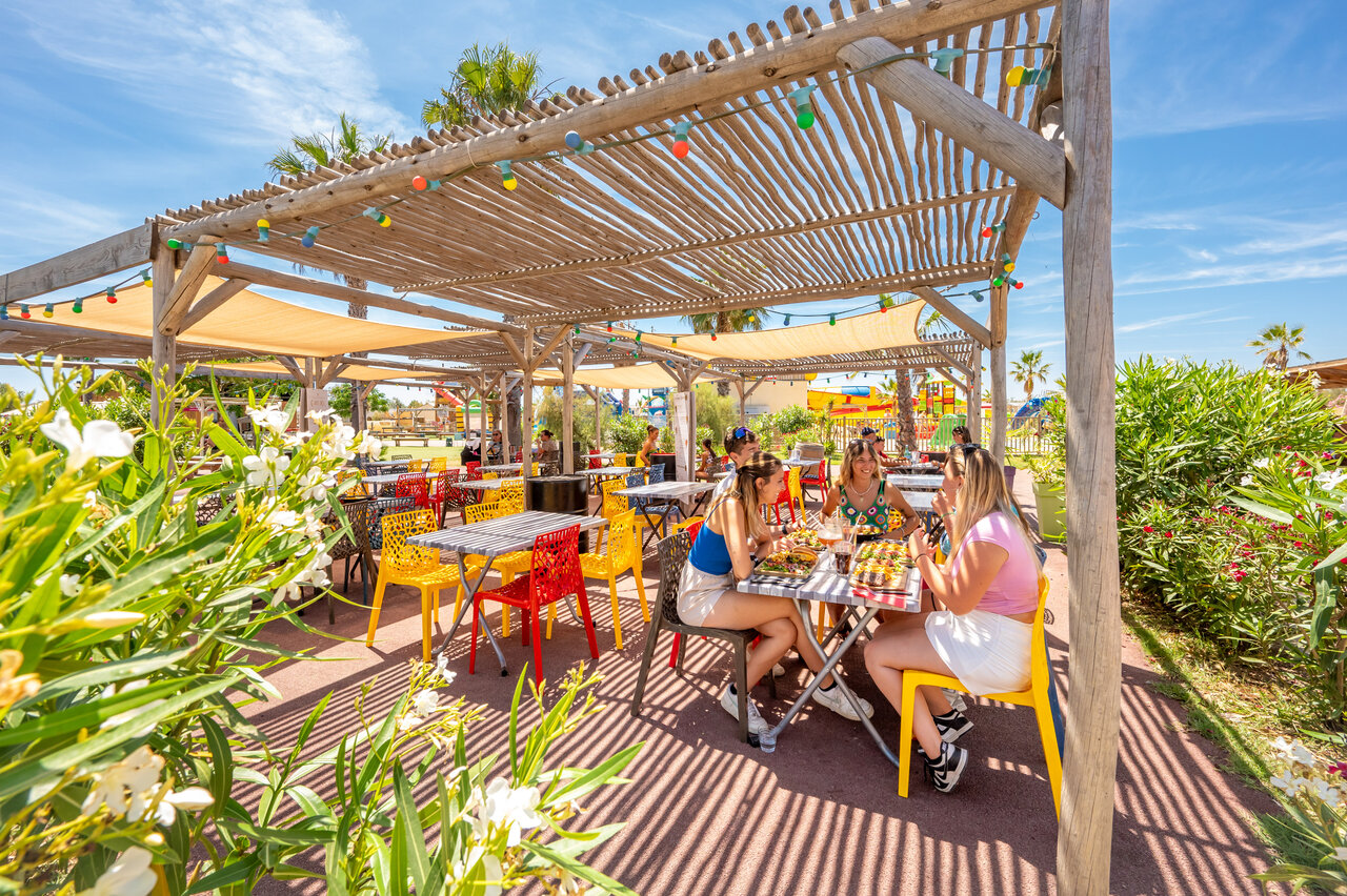 Outdoor restaurant, pergola, guests at VAGUES OCEANES Hamacs campsite in Fleury (11).