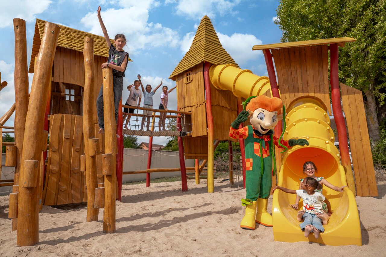 Wooden playground, slides, children and mascot at camping CLICOCHIC Haras de Deauville.