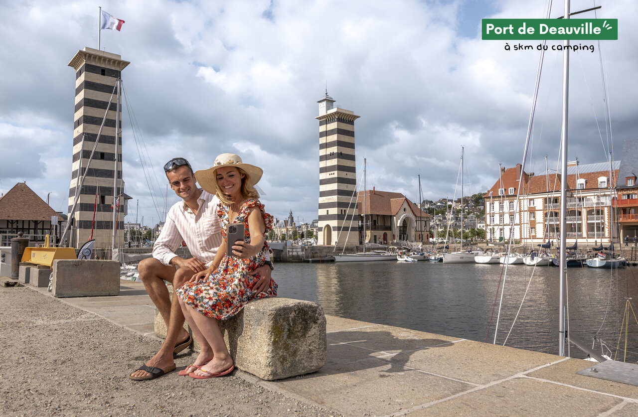 Couple taking selfie at Deauville Port, a place to visit in Normandy.