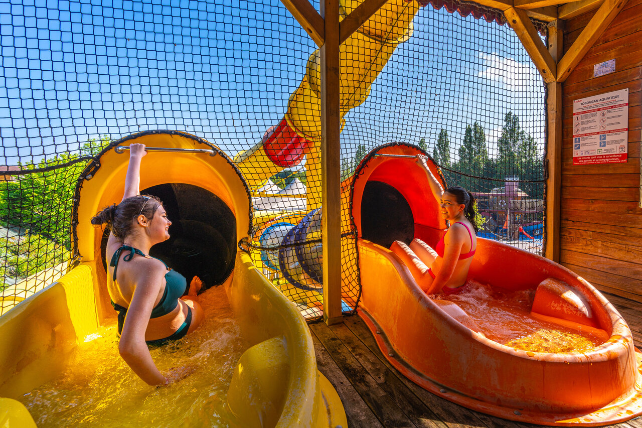 Two young women on yellow and orange water slides at CAPFUN Hautes Coutures campsite in BENOUVILLE (14).