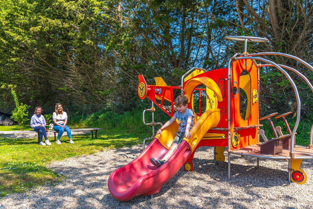 Child on colorful slide in the playground at CAPFUN Hautes Coutures campsite in BENOUVILLE (14).
