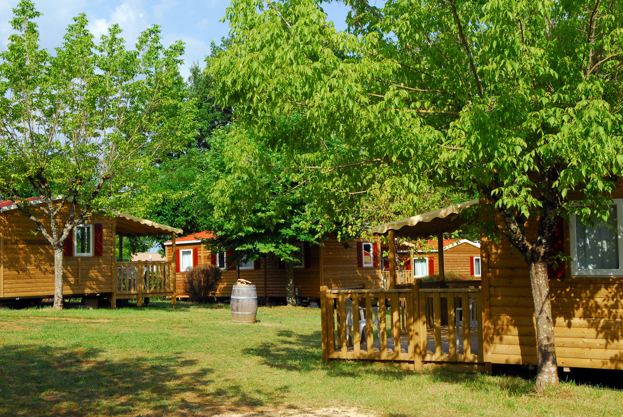 Wooden chalets, terraces and trees at CAPFUN Hauts de Ratebout in STE FOY DE BELVES (24).