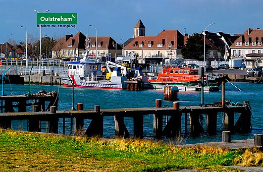 Ouistreham harbor with fishing boats and buildings, coastal town in Normandy.