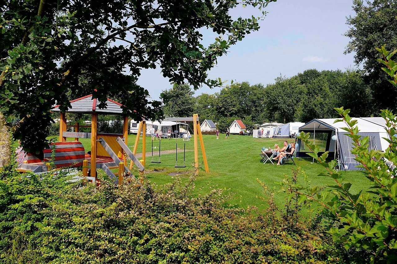 Playground with swings and slide, camping pitches at CAPFUN Heino campsite.