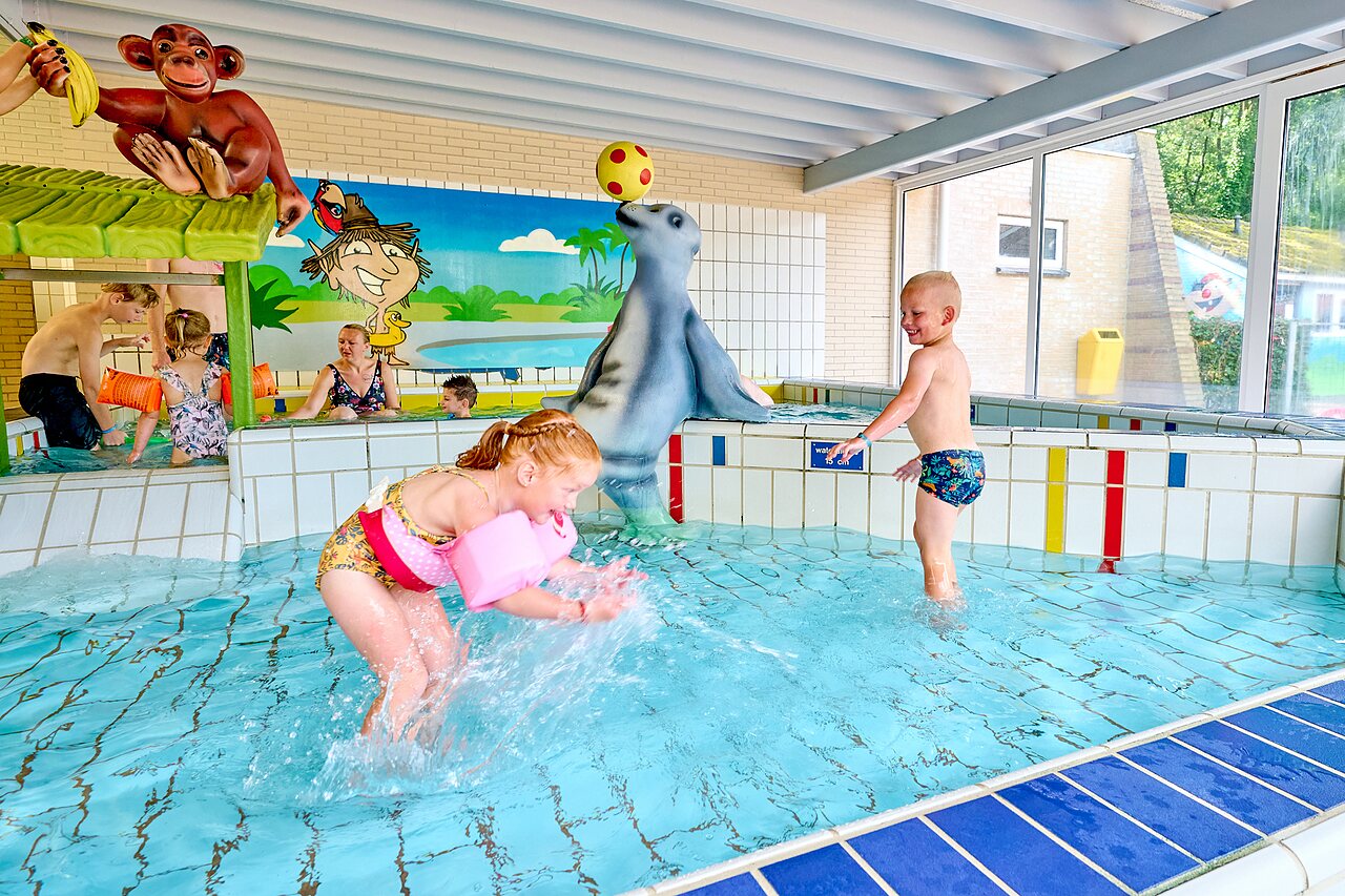 Indoor swimming pool with water games and children at CAPFUN Heino campsite in Heino.