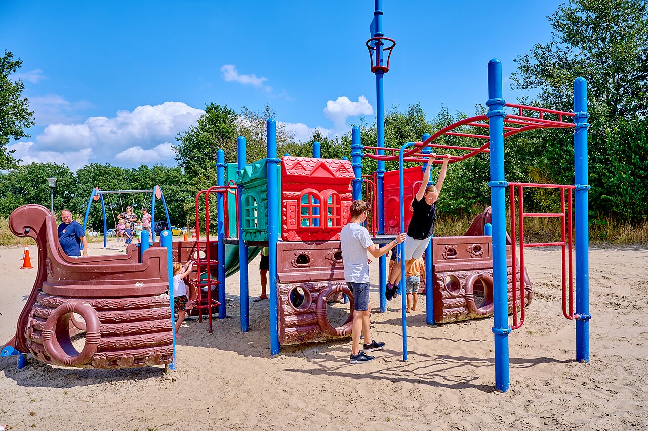 Colorful playground with structures, slides and swings at CAPFUN Heino campsite.