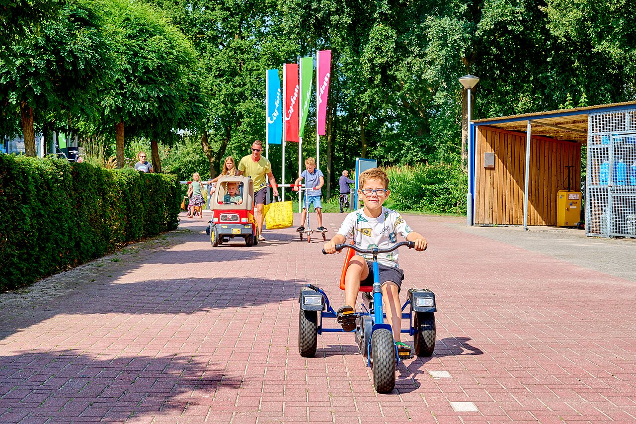 Children playing with pedal kart, scooter and toy car at CAPFUN Heino in Heino.