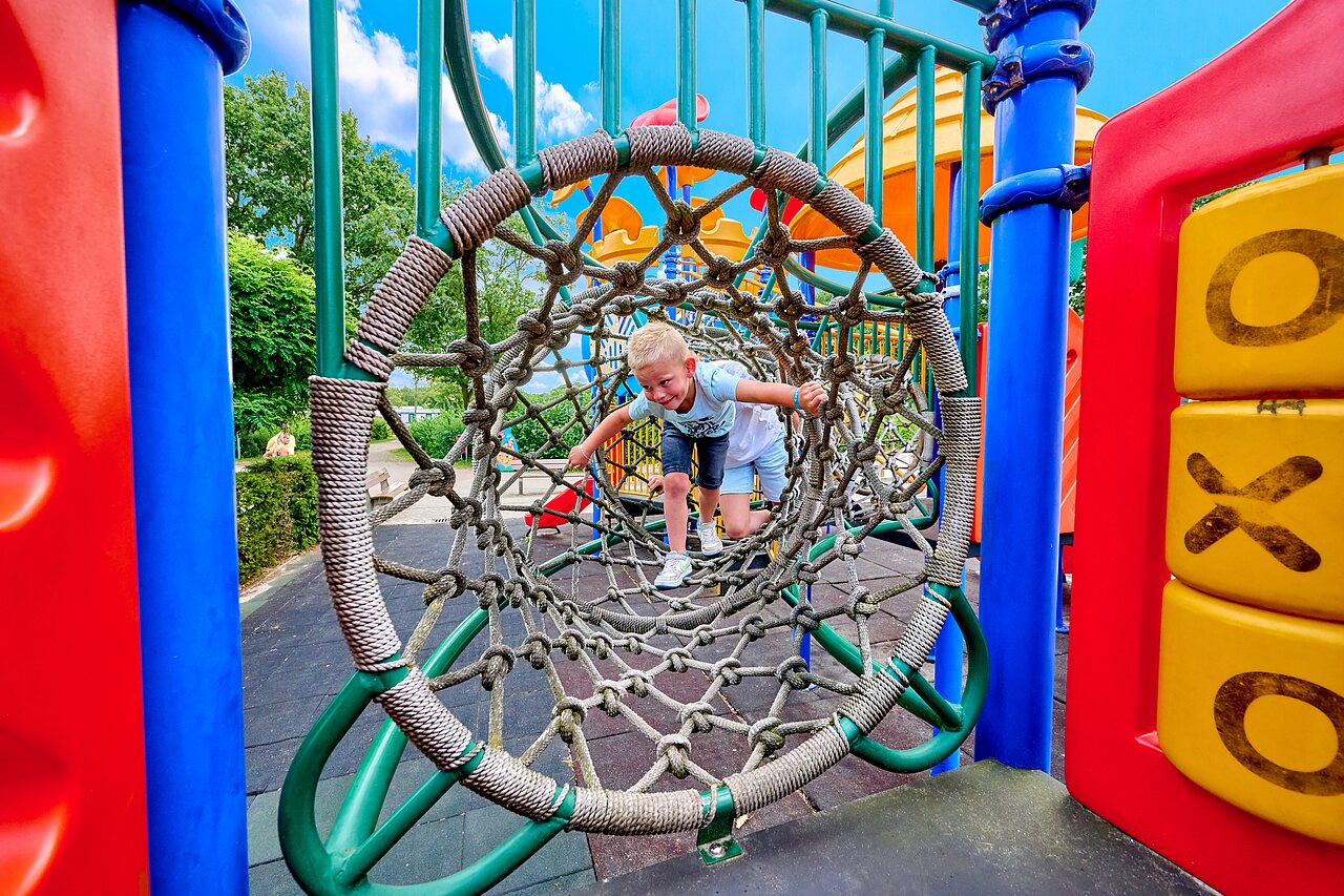 Smiling child in rope tunnel on playground at CAPFUN Heino.