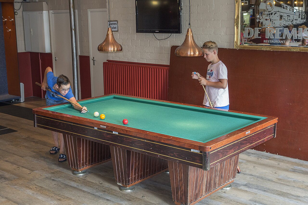 Kids playing billiards in the games room at CAPFUN Heino campsite in Heino.