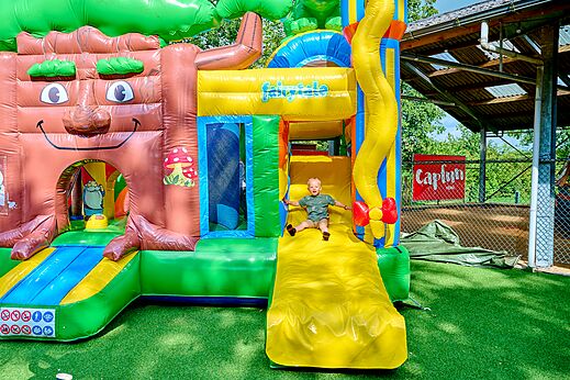 Child on giant inflatable slide at CAPFUN Heino campsite in Heino.