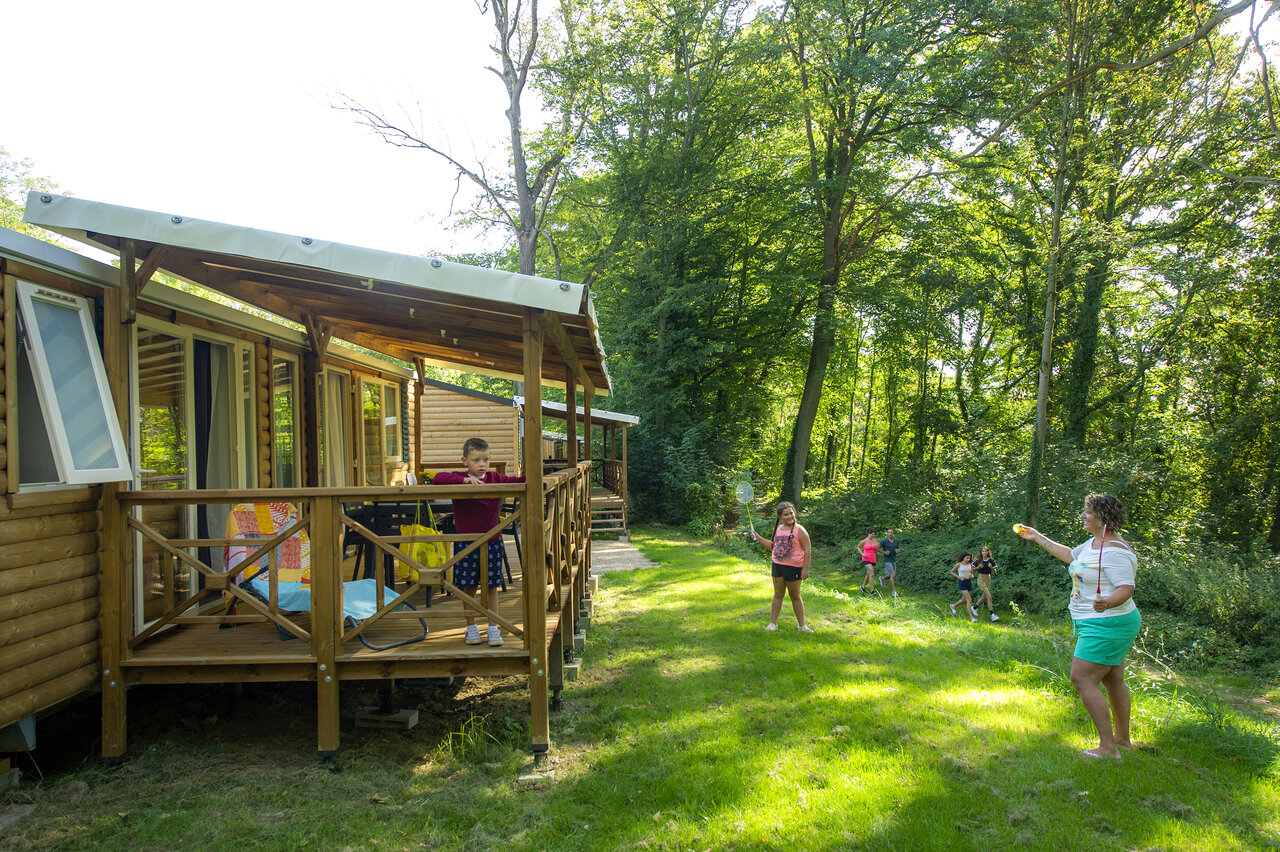 Wooden mobile home, children playing badminton at CAPFUN Hirondelle campsite in Oteppe.