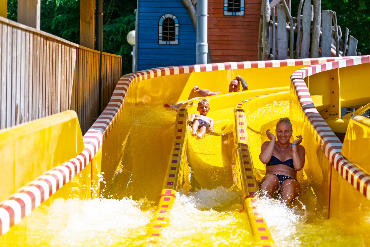 Family enjoying the yellow water slide at CAPFUN Hirondelle campsite in Oteppe.