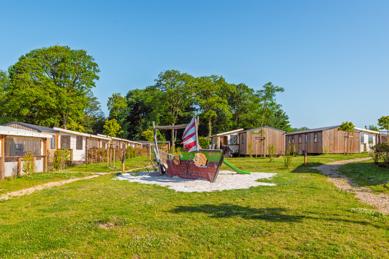 Pirate ship playground and wooden mobile homes at CAPFUN Hirondelle campsite in Oteppe.