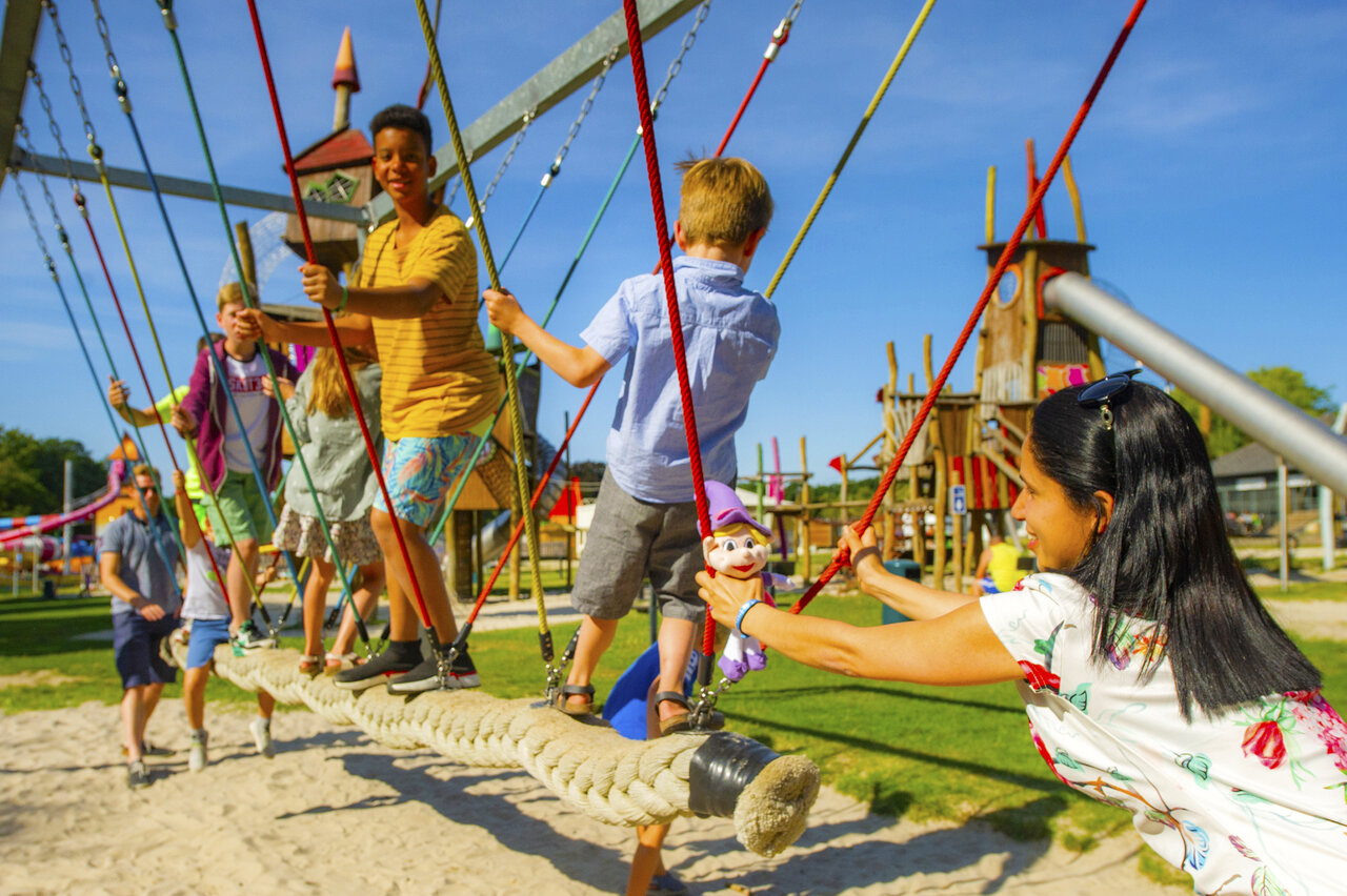 Playground with rope bridge and children at CAPFUN Hirondelle campsite in Oteppe.