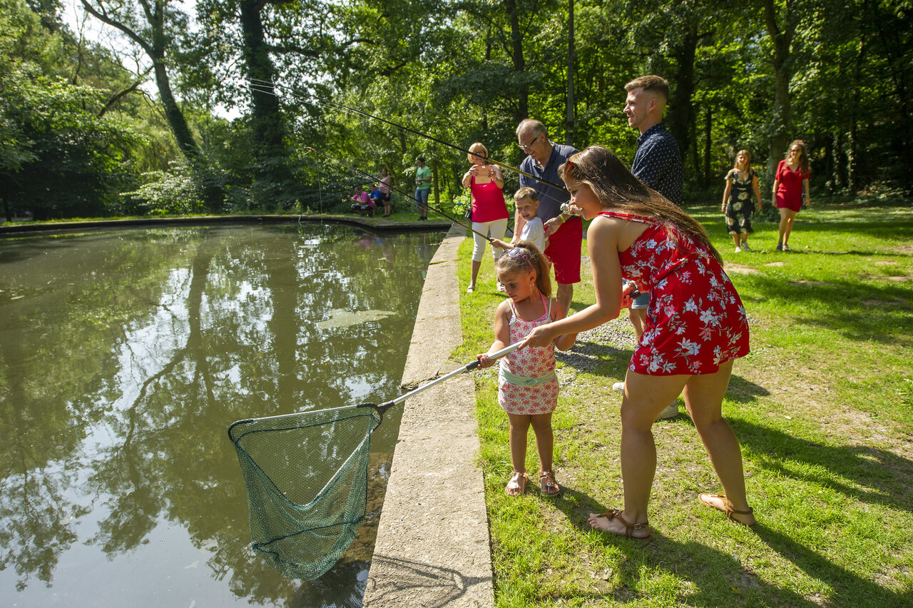 Family fishing with a net by the pond at CAPFUN Hirondelle campsite in Oteppe.