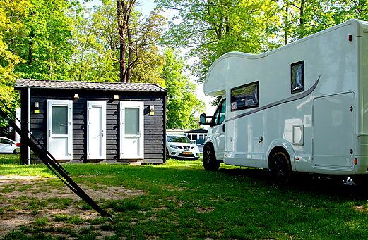 Sanitary block and white Mobile home on grassy pitch at CAPFUN Hirondelle Oteppe.