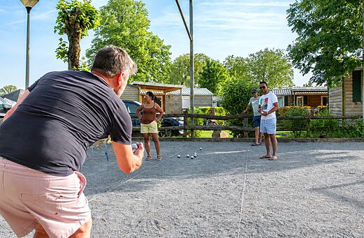 Petanque court with holidaymakers playing boules at CAPFUN Hirondelle campsite in Oteppe.