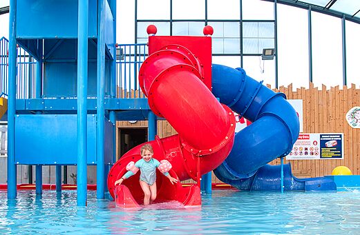 Water slide and swimming pool with smiling child at CAPFUN Hirondelle Oteppe.