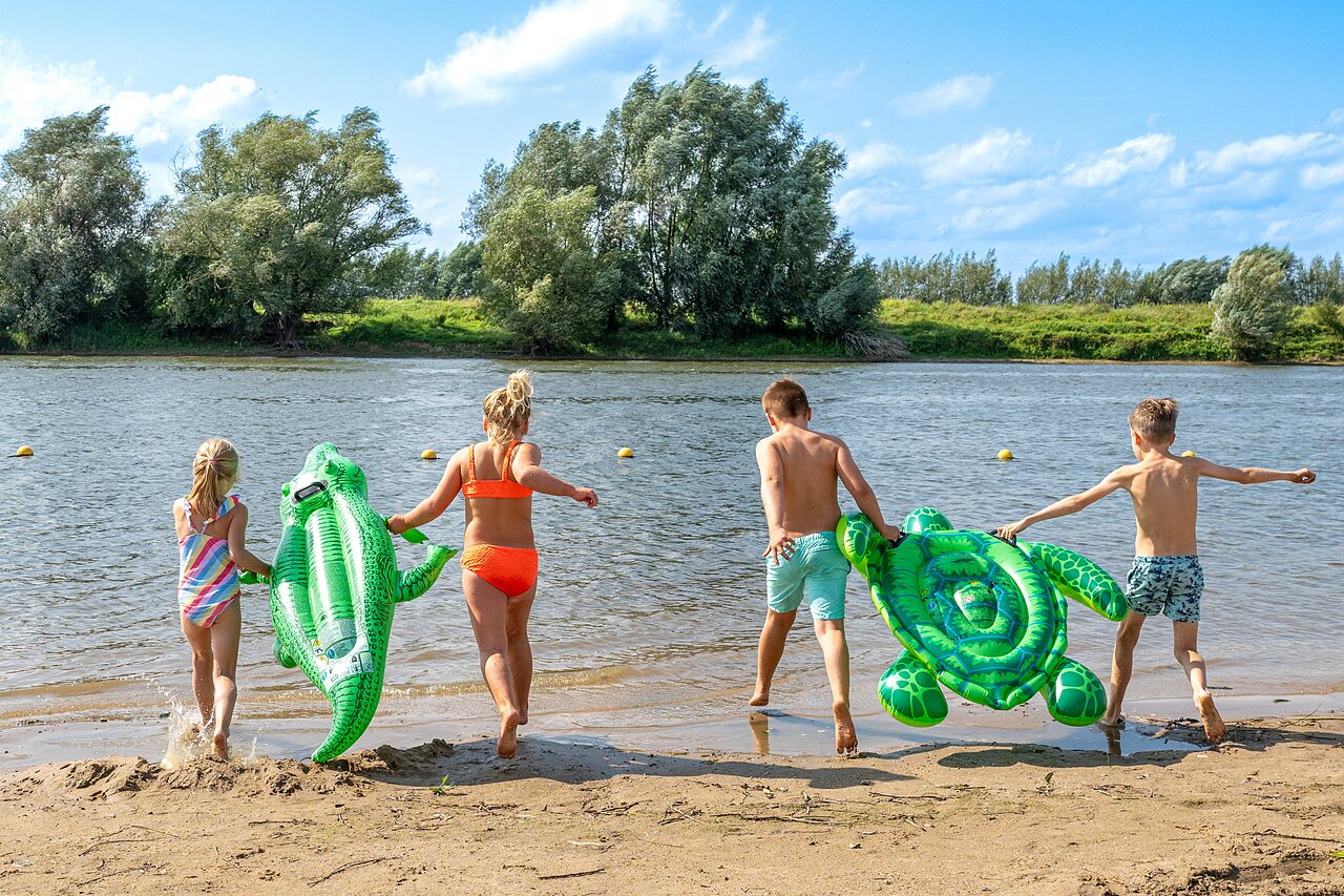 Children with inflatable toys on sandy beach at CAPFUN IJsselstrand campsite in Doesburg.