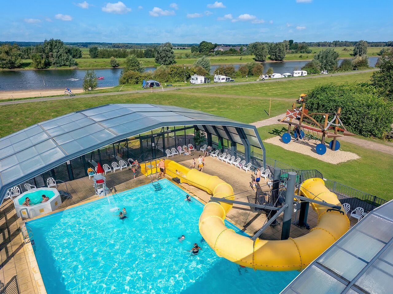 Outdoor swimming pool with giant slide, jacuzzi and playground at CAPFUN IJsselstrand campsite in Doesburg.