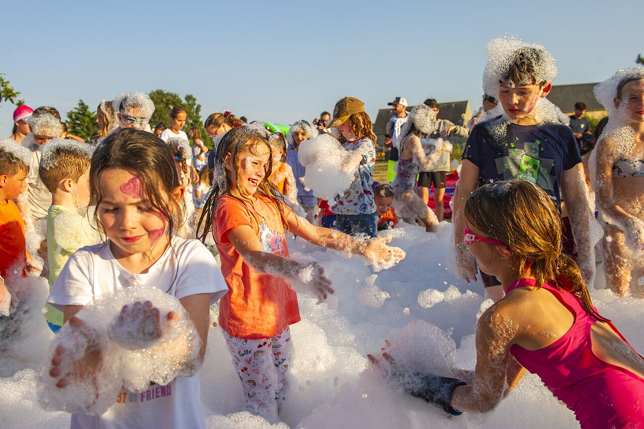 Joyful children enjoying an outdoor foam party at CAPFUN IJsselstrand campsite in Doesburg.