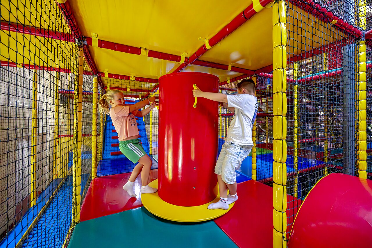 Children playing on a colorful indoor play structure at CAPFUN IJsselstrand campsite in Doesburg.