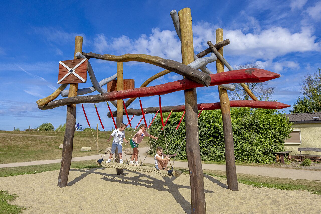 Children playing on wooden and rope playground structure at CAPFUN IJsselstrand campsite in Doesburg.