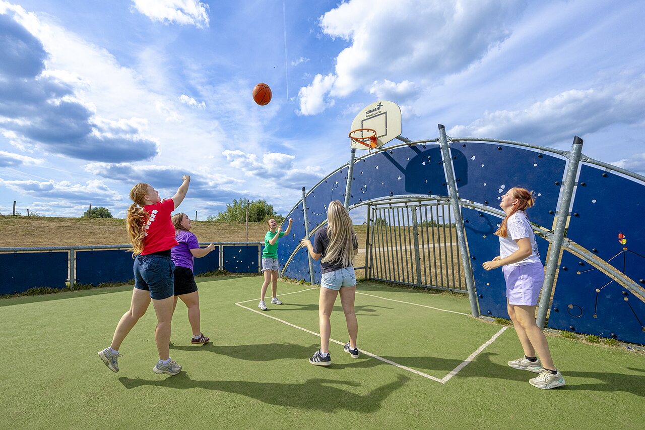 Young people playing basketball on multi-sport court at CAPFUN IJsselstrand, Doesburg.