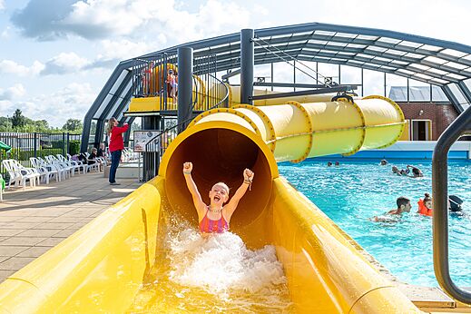 Yellow water slide and outdoor pool at CAPFUN IJsselstrand campsite in Doesburg.