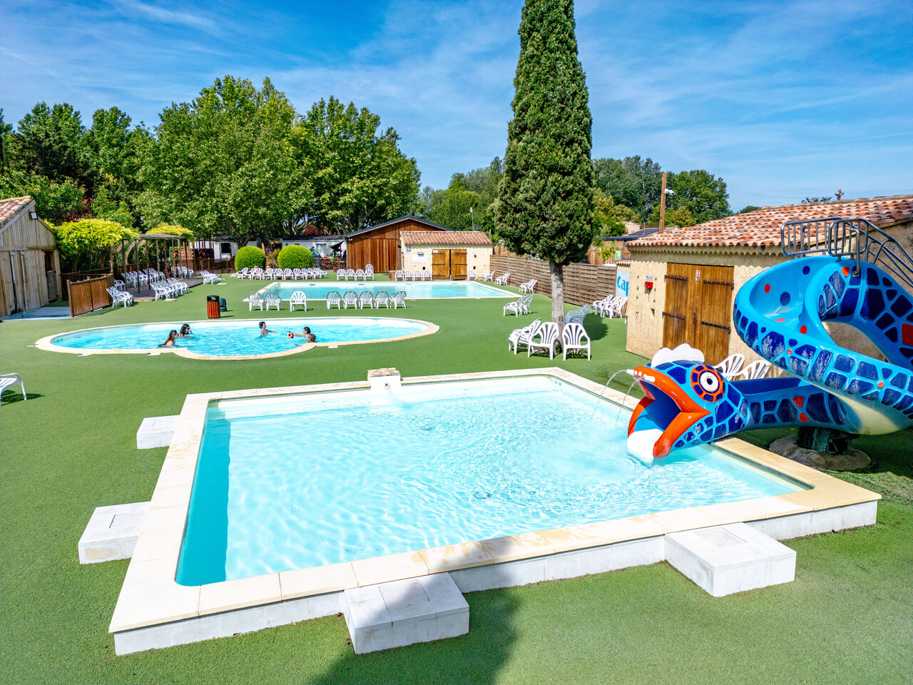 Outdoor pools with snake slide and sun loungers at CAPFUN Jantou campsite in LE THOR (84).