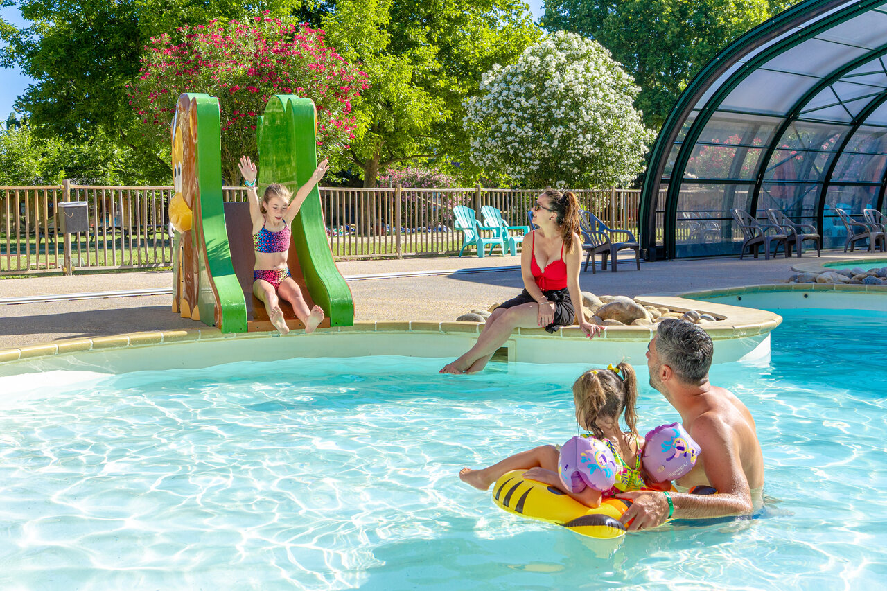 Child on slide and family enjoying the swimming pool at CAPFUN Jantou campsite in LE THOR (84).