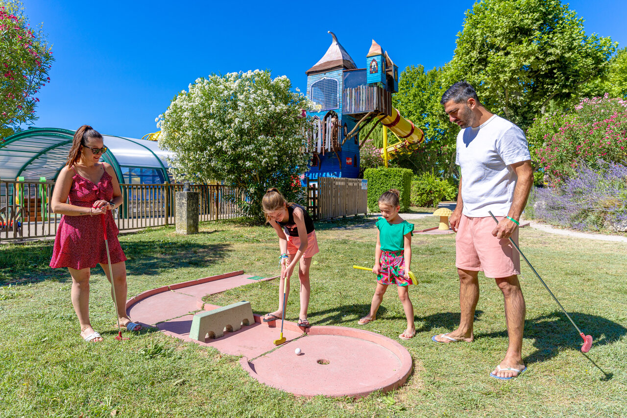 Family playing mini-golf with playground and swimming pool at CAPFUN Jantou campsite in LE THOR (84).